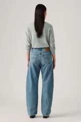 Pantalón de jean de corte baggy con diseño barrel, tiro medio y lavado azul claro con efecto desgastado. Presenta costuras laterales curvadas que definen su silueta amplia y relajada.