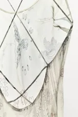 Vestido midi de viscosa con estampado floral y geométrico en tonos neutros. Presenta escote redondo, tirantes finos cruzados en la espalda con ajuste de lazada y forro interior.