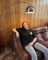 Remera negra de corte oversize con estampa gráfica en la espalda que simula un paquete de yerba mate, con ilustración de una mujer rubia y texto alusivo.