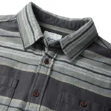 Camisa de franela a rayas horizontales en tonos grises, con cuello clásico, manga larga, cierre frontal con botones marrones, dos bolsillos con botón en el pecho y puños abotonados.