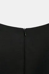 Vestido mono corto de cuello redondo y sin mangas. Presenta un diseño entallado con detalle de cinturón del mismo tejido con hebilla metálica y cierre de cremallera oculta en la espalda.