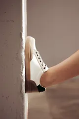 Zapatillas urbanas de cuero ecológico blanco con puntera y talón de gamuza sintética color beige. Cordones negros y suela de goma color caramelo.