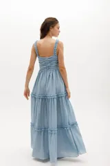 Vestido largo blanco de gasa de algodón con textura liviana. Tiene escote en V con nudo central, breteles con voladitos y falda con frunces.