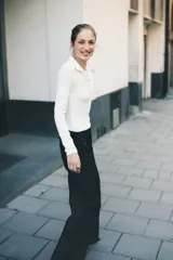 Remera polo de manga larga color blanco, confeccionada en tejido de punto acanalado. Presenta cuello clásico y tapeta frontal con botones dorados.