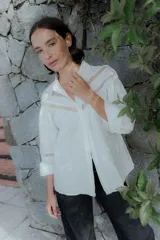 Camisa negra de algodón con detalles de encaje broderie en el pecho y mangas. Presenta cuello clásico, cierre frontal con botones y mangas largas abullonadas.