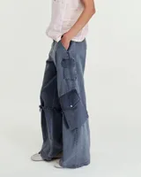 Pantalón cargo de tiro medio confeccionado en gabardina de algodón y lino con efecto gastado. Presenta una silueta de pierna recta y ancha, con bolsillos laterales inclinados y bolsillos cargo con tapa en las rodillas. Incluye tiras ajustables con hebillas metálicas en los laterales para modificar la silueta, cierre metálico y bolsillos traseros.