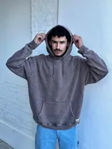 Buzo canguro marrón con capucha y cordones, de corte amplio y estilo urbano.