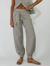 Pantalón de lino color rojo, de corte holgado con botamangas elastizadas y diseño cruzado en la cintura con lazo ajustable.