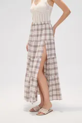 Falda larga de algodón con diseño a cuadros en tonos beige, blanco, marrón y celeste. Presenta un diseño escalonado con volados y una abertura lateral pronunciada.