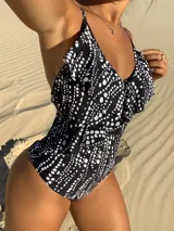 Malla enteriza negra con estampado de lunares blancos, breteles finos y volados en el escote.