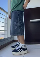 Bermuda de jean gris oscuro, corte ancho y largo a la rodilla, con diseño de estrella rota en el muslo.