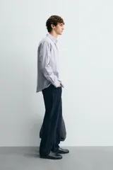 Camisa de corte regular fit confeccionada en tejido de algodón con diseño de rayas verticales. Presenta cuello abotonado, manga larga con puños abotonados y cierre frontal de botones.