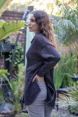 Camisa tejida en punto calado color marrón con hilo de algodón y lurex. Silueta oversize, mangas 3/4 ligeramente abullonadas, cuello camisero clásico y botonadura frontal con botones metálicos dorados.