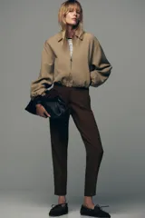 Chaqueta bomber negra con cuello solapa, manga larga abullonada y puños elásticos. Presenta falsos bolsillos de doble vivo en la parte delantera y cierre frontal con cremallera.