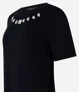 Blusa blanca de mangas cortas confeccionada en viscosa con cuello redondo con brillos en formas florales.