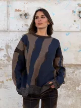 Sweater de tejido de punto con diseño abstracto de rayas irregulares en tonos azul y marrón. Presenta cuello redondo, mangas largas con caída de hombro y puños y ruedo acanalados.