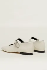 Zapato plano estilo Mary Jane de cuero negro, con punta fina y tira ajustable con hebilla sobre el empeine.