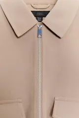 Cazadora de cuello solapa y manga larga, color verde militar, con bolsillos delanteros de plastrón con solapa, bajo elástico y cierre frontal con cremallera.