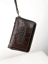 Mini billetera de cuero con textura efecto cocodrilo y cierre perimetral. Presenta un parche central con el logo de la marca grabado.