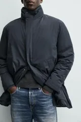 Parka acolchada impermeable color gris oscuro, de corte regular fit, con cuello doble subido, bolsillos de vivo en la cadera y cierre frontal con cremallera oculta por solapa con botones a presión.