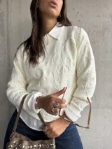 Sweater de punto color natural con diseño de relieve floral en toda la prenda, cuello redondo y mangas largas con puños acanalados.
