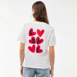 Camiseta de manga corta color blanco con cuello redondo y pequeño corazón rojo estampado en el pecho.