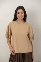 Remera de algodón color blanco, con cuello redondo y mangas cortas holgadas que presentan detalles de encaje broderie.