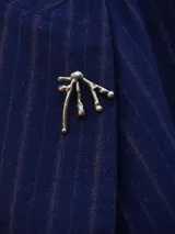 Pin plateado con forma abstracta de ramas con gotas.