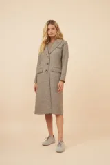 Tapado largo de corte recto confeccionado en lana fina sin teñir. Presenta cuello solapa, cierre frontal con botones, bolsillos laterales con tapa y detalles aplicados en la parte delantera. Incluye forro interior y tajo en la espalda.