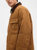 Campera acolchada de color marrón, con cierre frontal de botones a presión, cuello de pana en tono más oscuro y bolsillos frontales tipo parche.