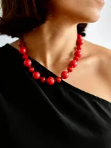 Collar de cuentas esféricas de color rojo intenso, con cadena de acero quirúrgico para regular el largo.