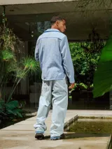 Camisa de lino rayada en tonos celeste y blanco, con cuello y botones frontales. Presenta un estampado en el frente y la espalda.