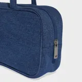 Bolso tipo airliner de Adidas confeccionado en tejido denim azul. Presenta un diseño alargado con manijas largas para llevar al hombro, cierre principal y logo del Trifolio metálico en la parte frontal.