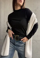 Remera negra de cuello alto y manga larga, confeccionada en tejido de algodón con textura acanalada.