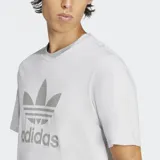 Remera gris claro de corte clásico con cuello redondo y logo Adidas Trifolio estampado en el frente.