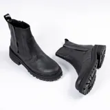 Bota tipo Chelsea de cuero vacuno color negro, con suela de goma track de estilo deportivo y elástico lateral.