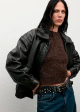 Chaleco de tejido bouclé color marrón, con cuello redondo y manga corta. Presenta un diseño recto y textura suave.