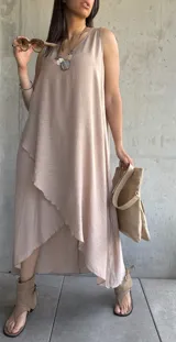 Vestido largo color beige, sin mangas, con escote redondo y corte irregular con volados.