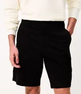 Bermuda de sarga negra de corte recto y holgado para hombre, con bolsillos cargo laterales con solapa, cintura con pasadores y cierre frontal con botón y cremallera.
