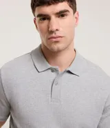 Remera polo gris de algodón con textura acanalada vertical, cuello tradicional y manga corta.