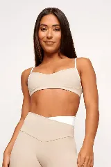 Top deportivo color beige con tirantes finos blancos.