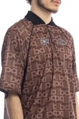 Remera deportiva marrón con cuello polo negro, cierre parcial con cremallera, mangas cortas y estampado con letras.