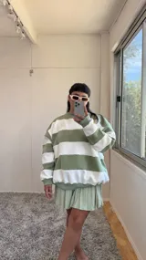 Buzo de corte oversize con diseño de rayas horizontales anchas en color verde y crudo. Presenta cuello redondo, mangas largas y puños elásticos, confeccionado en tela con interior de felpa.