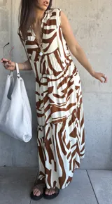 Vestido largo color blanco con estampado abstracto en marrón, con escote en V y corte escalonado.