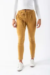 Pantalón de gabardina color mostaza, con cintura elastizada, cordón ajustable y bolsillos laterales. Corte ajustado al tobillo.