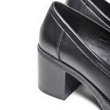 Zapato tipo mocasín de plataforma con taco alto y ancho, confeccionado en material sintético liso con acabado negro. Presenta un diseño clásico con antifaz tradicional en la capellada y punta redondeada.