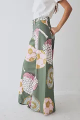Pantalon de corte wide leg y tiro alto, confeccionado en tela con estampado deportivo que incluye pelotas de futbol y raquetas de tenis en tonos verde, rosa y beige.