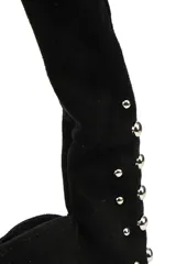 Cartera negra de poliéster con diseño de tachas metálicas plateadas en los bordes y en la correa. Tiene cierre superior y un compartimento principal.