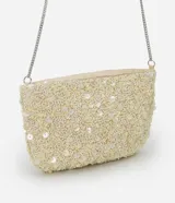 Cartera bandolera pequeña de forma rectangular, completamente cubierta de lentejuelas y cuentas brillantes en tono crema. Cuenta con cierre superior y una correa de cadena metálica plateada.