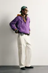 Pantalón cargo relaxed fit de color blanco, confeccionado en tejido de algodón. Presenta bolsillos de plastrón con solapa en las perneras y cierre frontal con cremallera y botón.